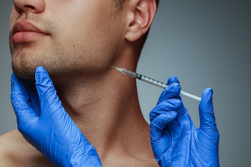 Reduce Pain of Injections Close-up portrait of young man isolated on grey studio background. Filling botox surgery procedure.